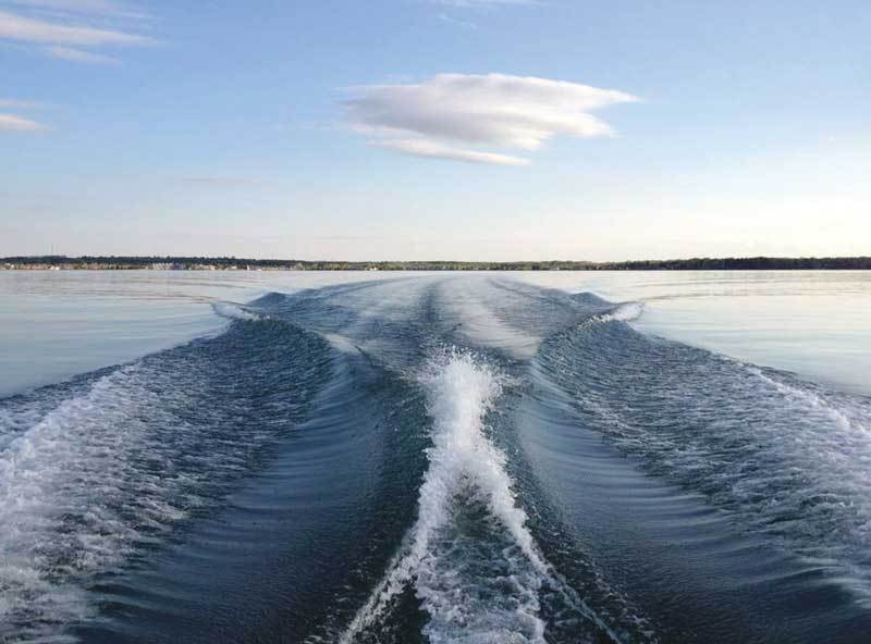 A boat is traveling on the water with wake behind it.